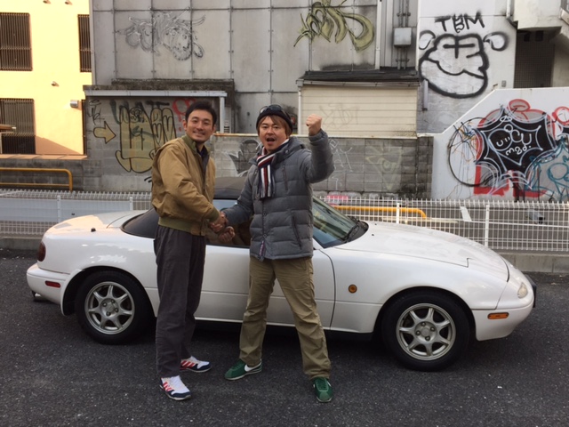 ▲兵庫県神戸市の某所で松元社長（左）から車両とキー、そして書類一式を受け取った筆者（右）