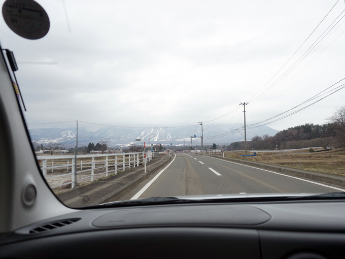 ▲中心部から少し離れると田んぼや畑が広がる。奥に見えるスキー場にはまだ雪が残っていた