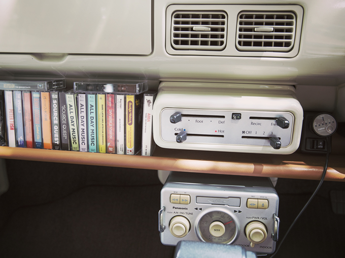 ▲真空管ラジオを思わせるデザインの純正オーディオは、カセットテープが再生できる。お店が製作したダッシュボードトレイには、カラフルなインデックスのミュージックテープが並ぶ