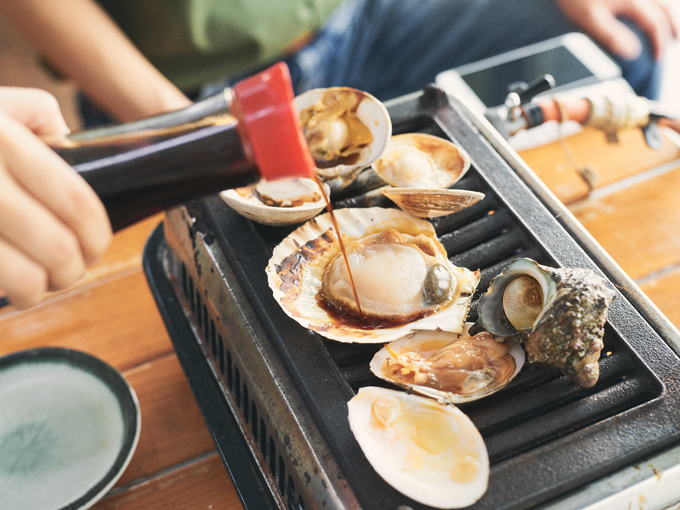 ▲貝汁が沸騰してきたら醤油を入れる。ジュワワワ～。かえ隊長も挑戦だ！ 思いっきり醤油を入れると……「隊長醤油入れすぎです！！！」と神崎隊員に叱られたのだ（笑） というのも、神崎隊員は浜焼きをスタートさせるとやたらと活きがよく動き始めたのだ。何やら浜焼き奉行なんだとか！ 初耳！